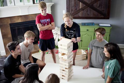 A group of teenagers playing Jenga together.