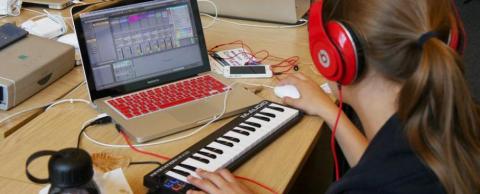 A teen playing with a keyboard on a laptop.