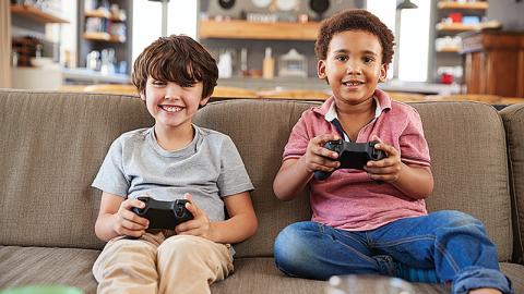 Two children playing video games on the couch.