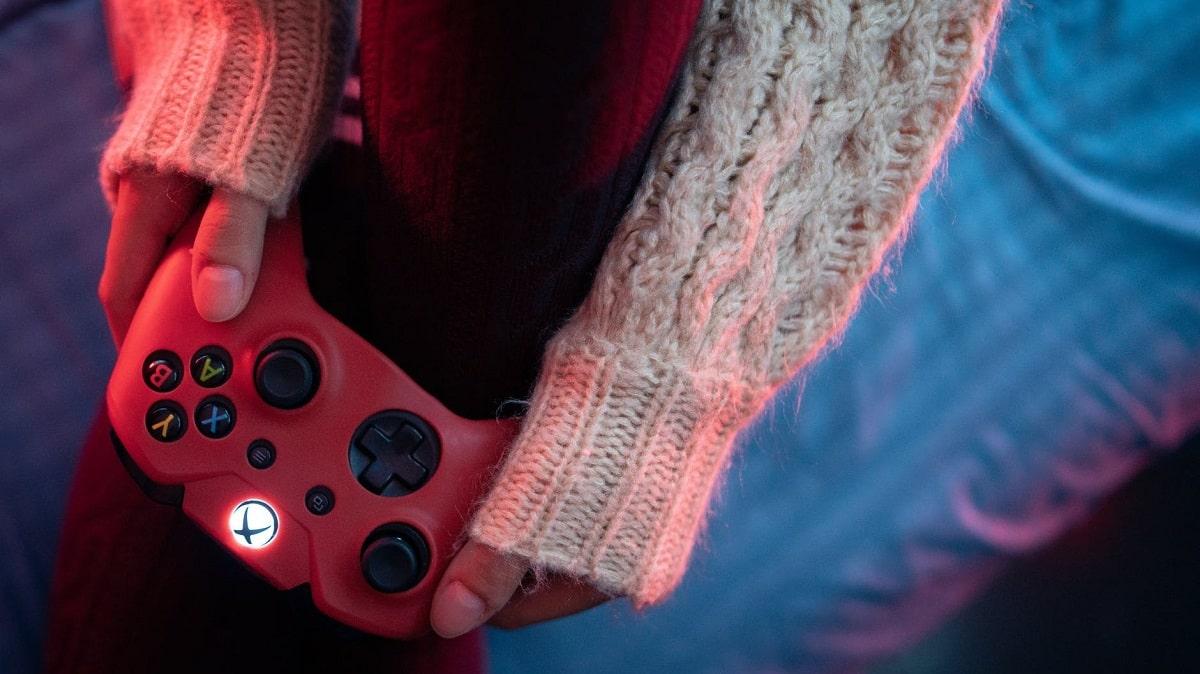 A person in a cozy sweater holding a game controller.